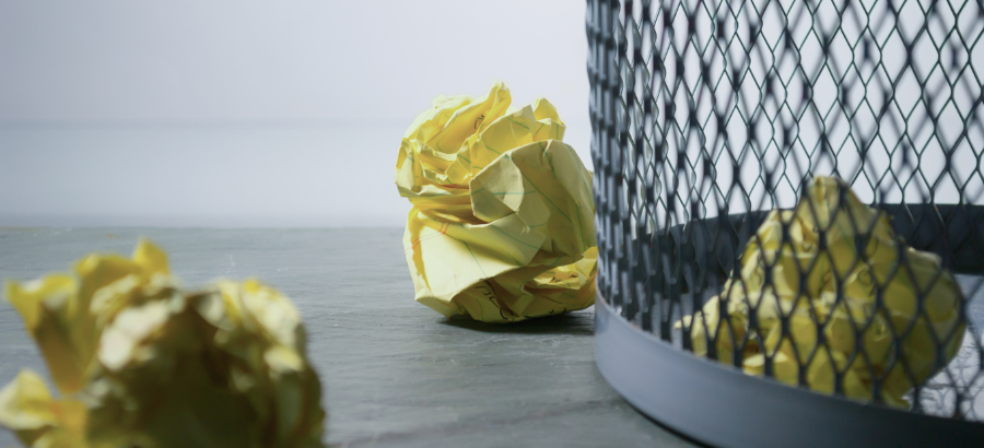 Crumbled yellow pages by a dustbin}