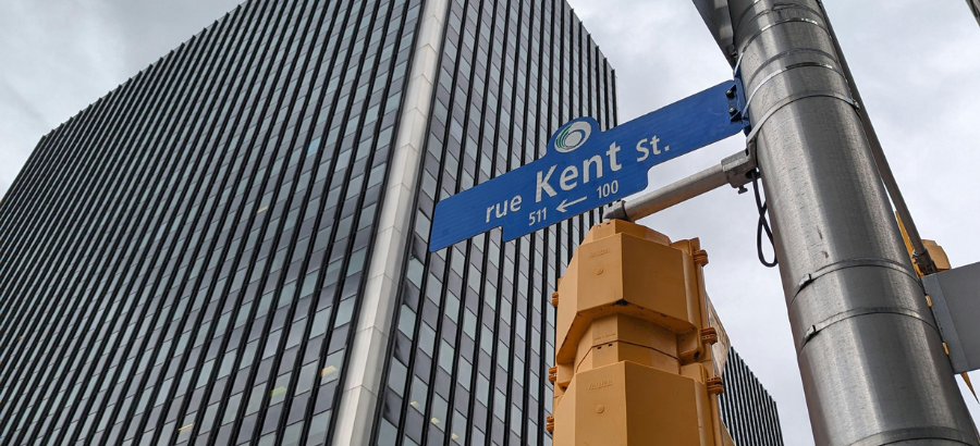 Blue street sign against a tall modern building in Ottawa, Canada
