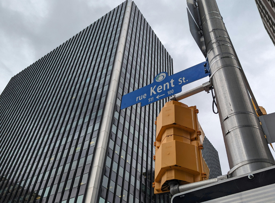 Blue street sign against a tall modern building in Ottawa, Canada