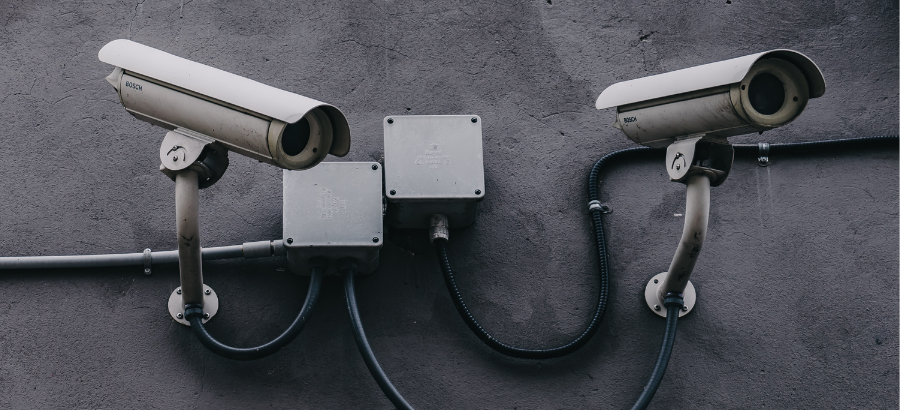 Two wall?mounted security cameras connected by cables on an exterior wall