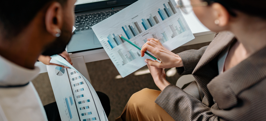 Charts and graphs being discussed over a laptop in a workplace setting