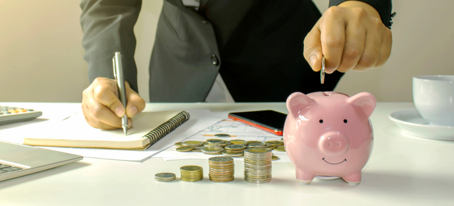 Man in formal clothes dropping coin into piggy bank}