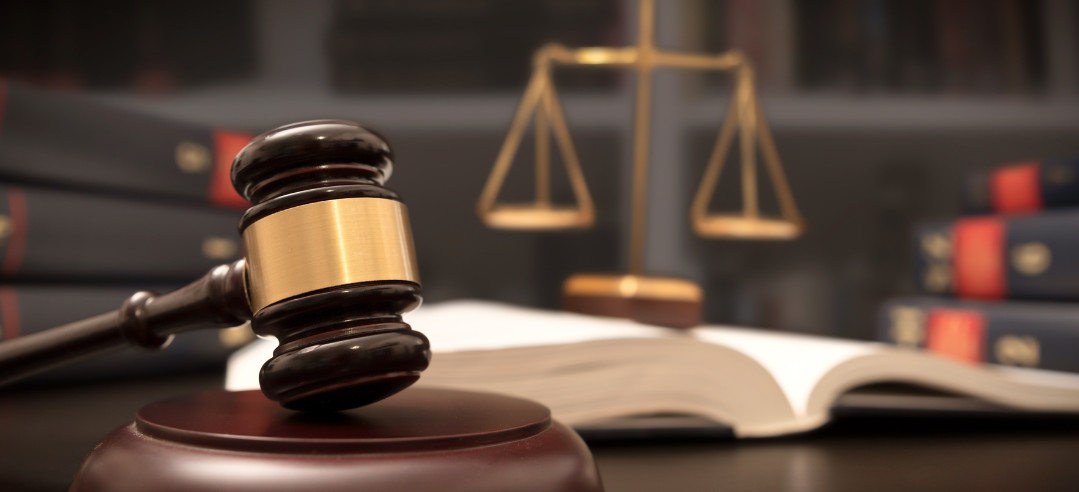 A gavel in a courtroom with a scale behind it 