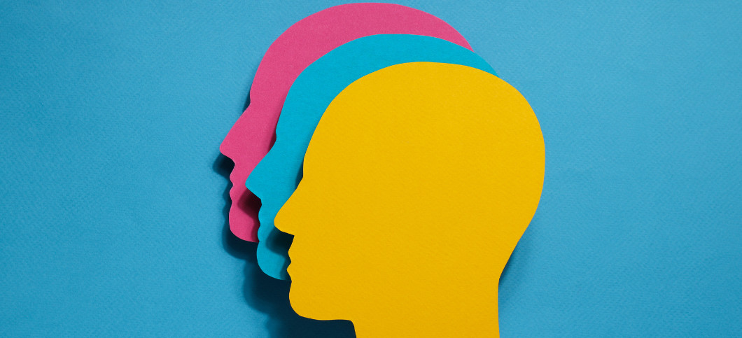 three cutouts of heads in three different colours, against a blue background